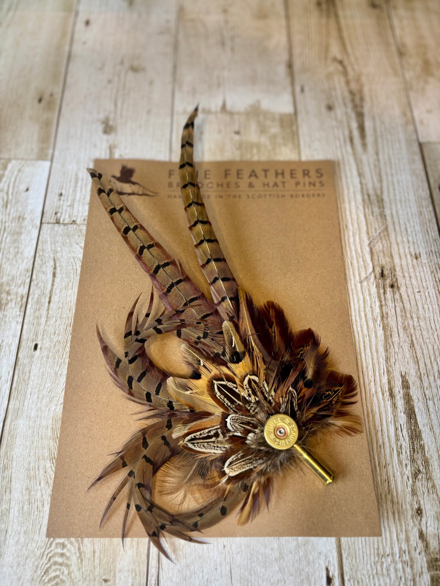 Pheasant feather hat pin with cartridge end and shell casing.