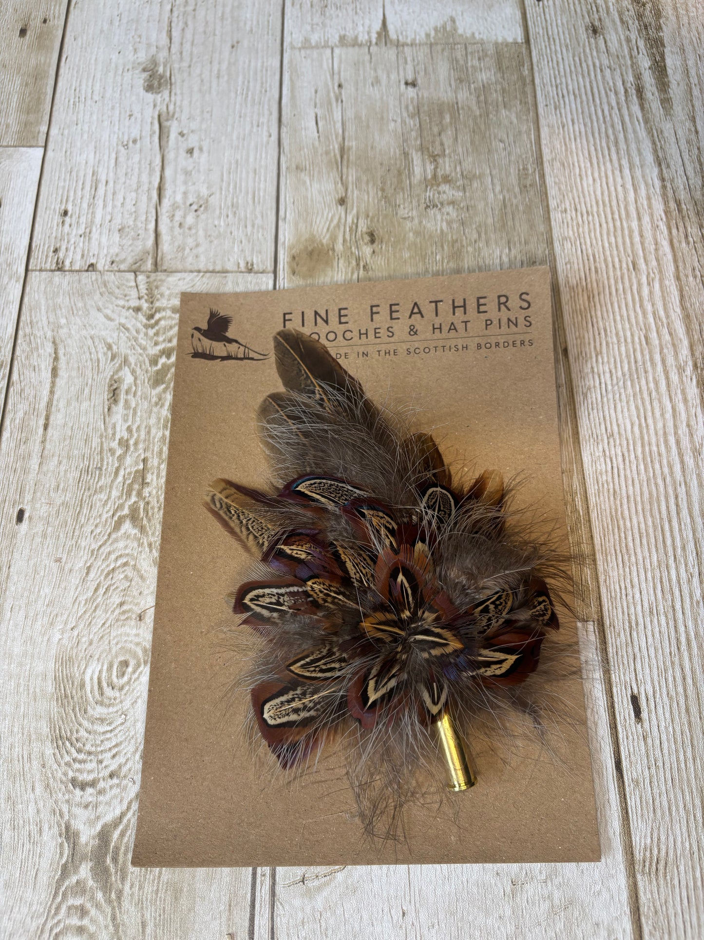 Pheasant feather hat pin with brass casing.